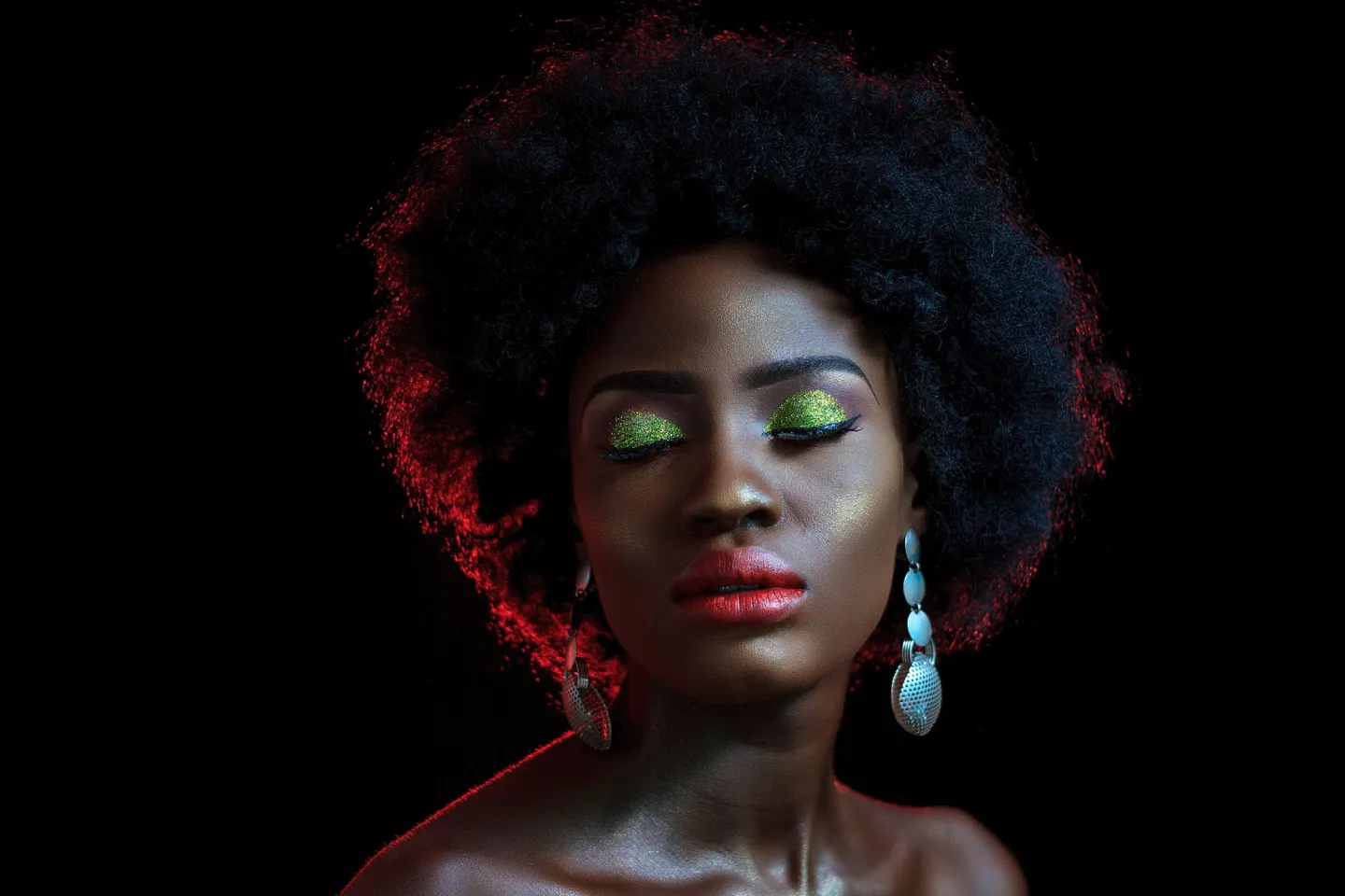 Model with green eyeshadow and red powder in the air